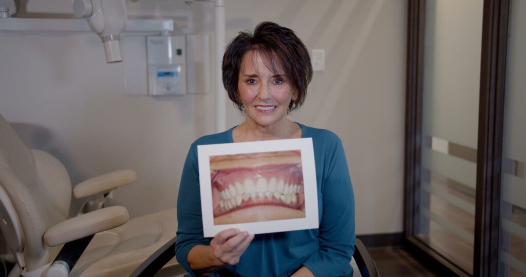 A woman is holding a picture of her teeth in a dental office.