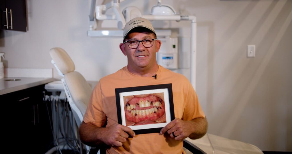 A man is holding a picture of his teeth in a dental office.