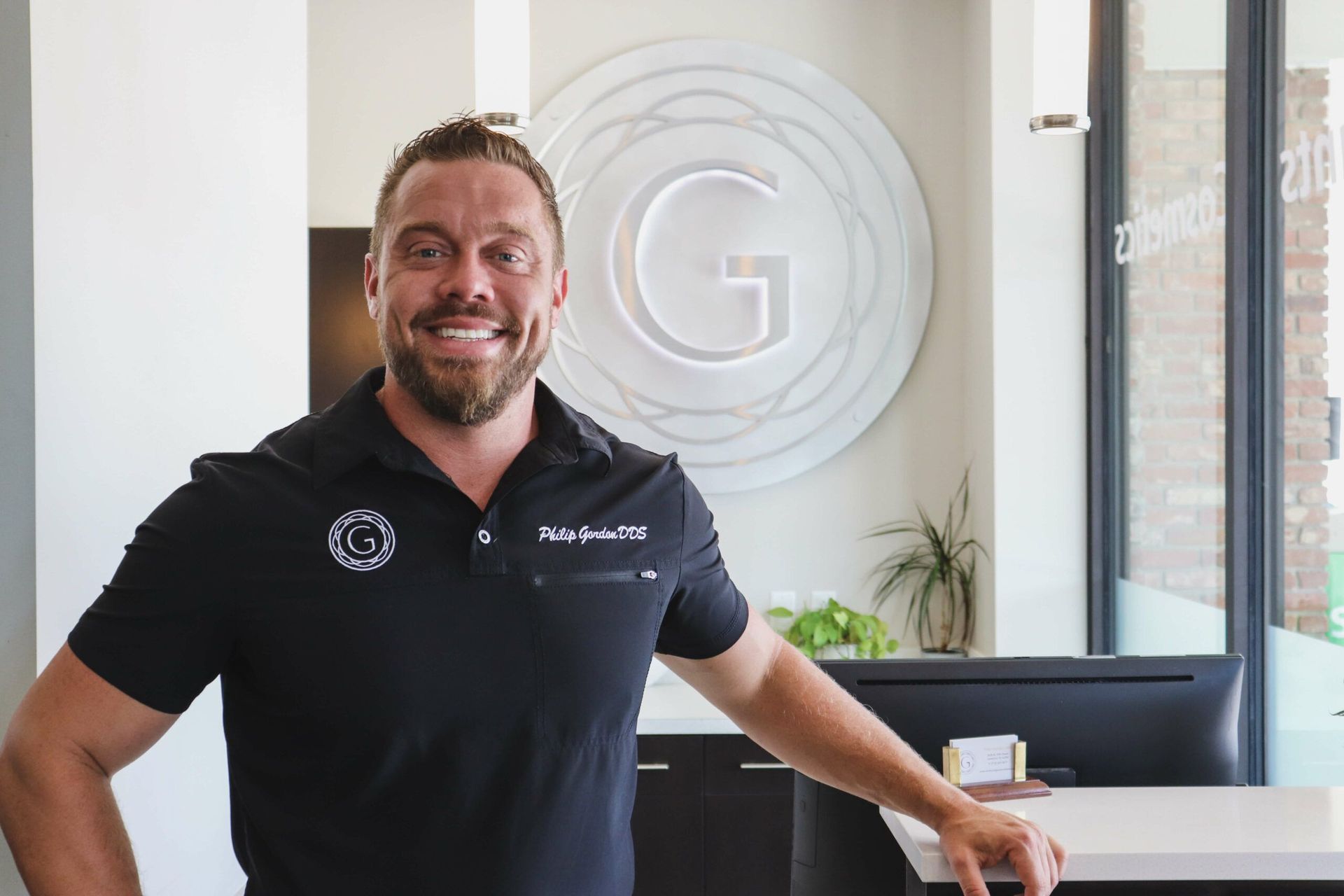 A man in a black shirt is standing in front of a sign that says g.