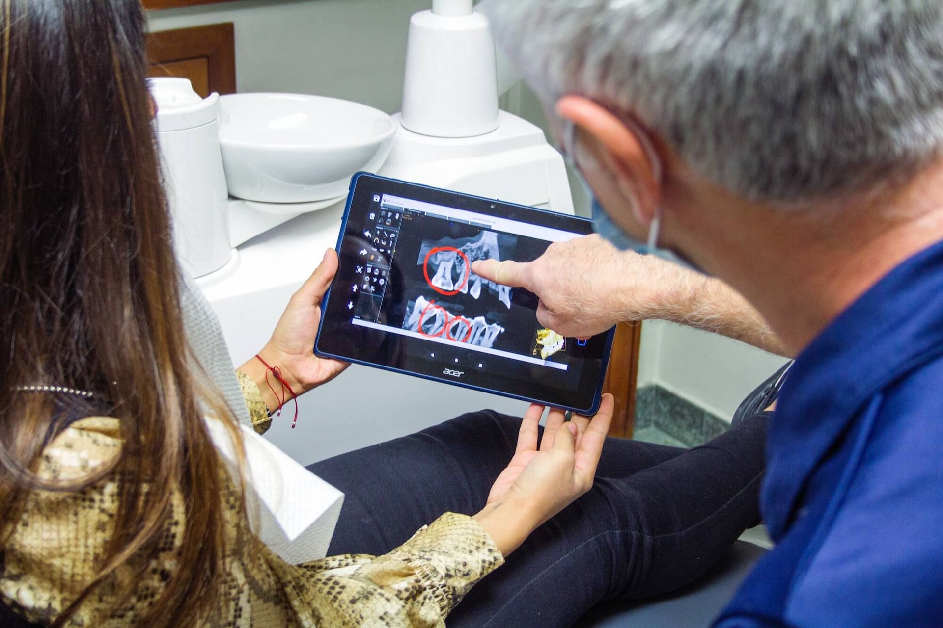 A man is pointing at a tablet screen while a woman looks on.