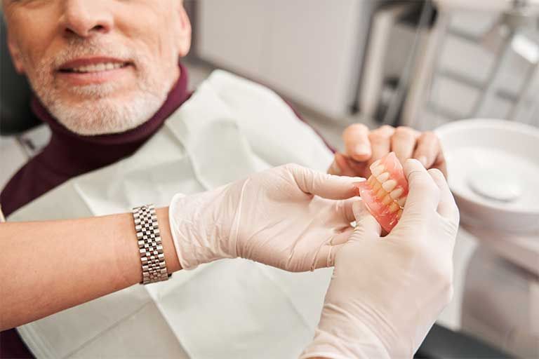 A man is sitting in a dental chair while a dentist examines his teeth.