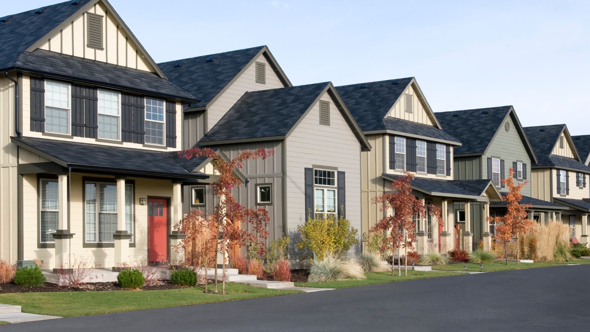 A row of houses with black roofs are lined up next to each other