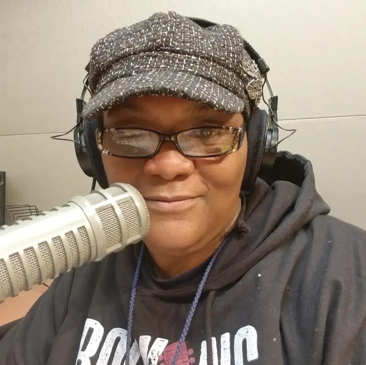 A woman wearing headphones and a hat is talking into a microphone