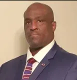 A man in a suit and tie is looking at the camera.