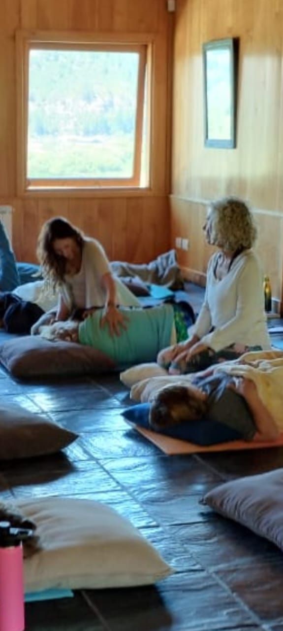 Las personas participan en una sesión grupal reparadora, algunas descansando sobre cojines en el suelo.