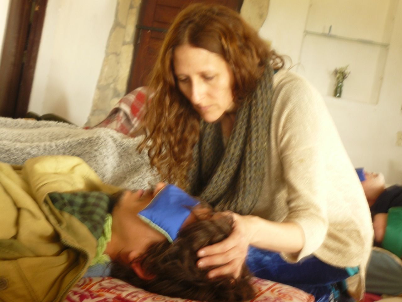 Una persona de cabello largo se inclina sobre otra persona que yace en una cama.