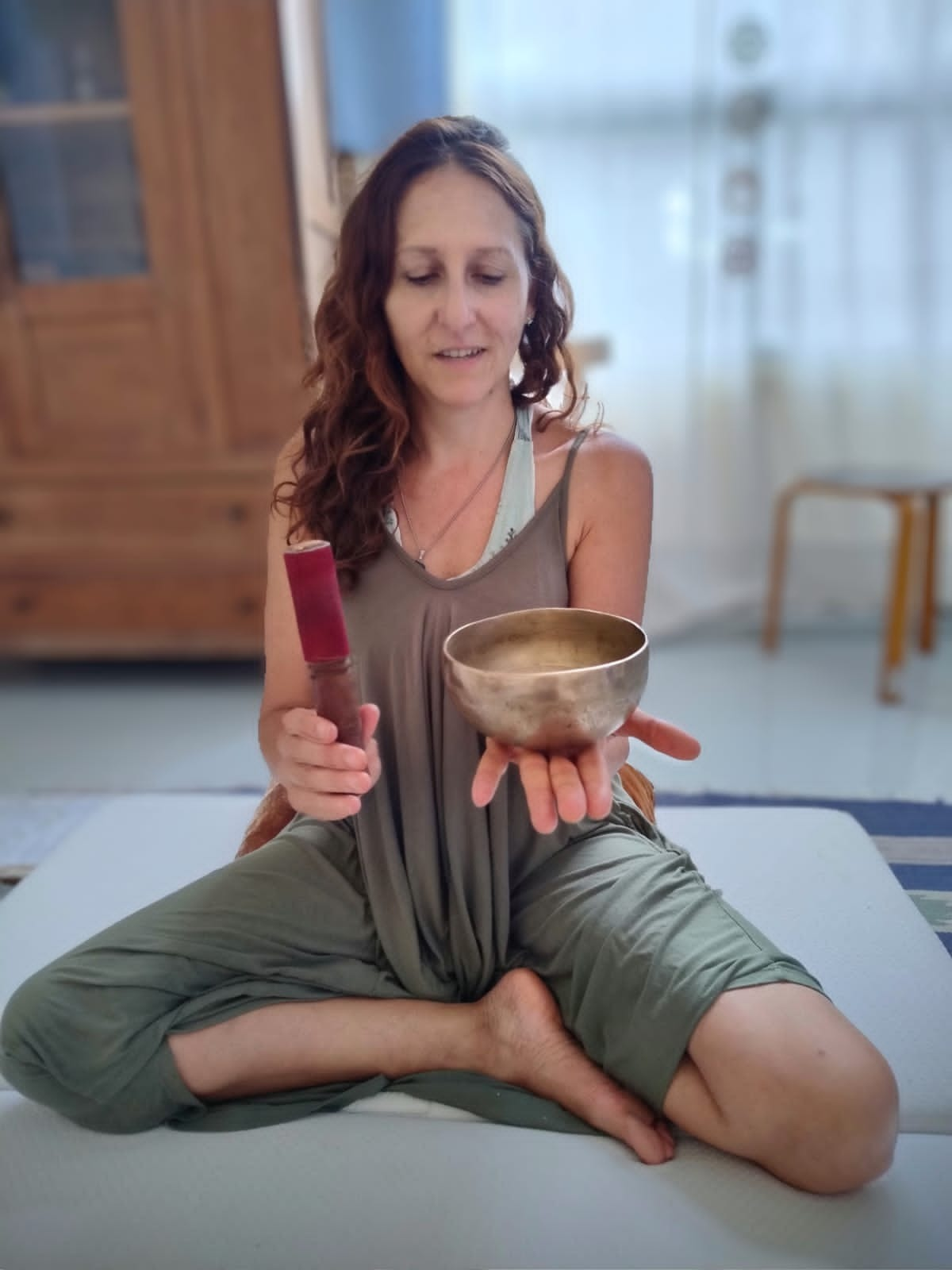 En una habitación muy iluminada, una persona vestida de color oliva está sentada con las piernas cruzadas.