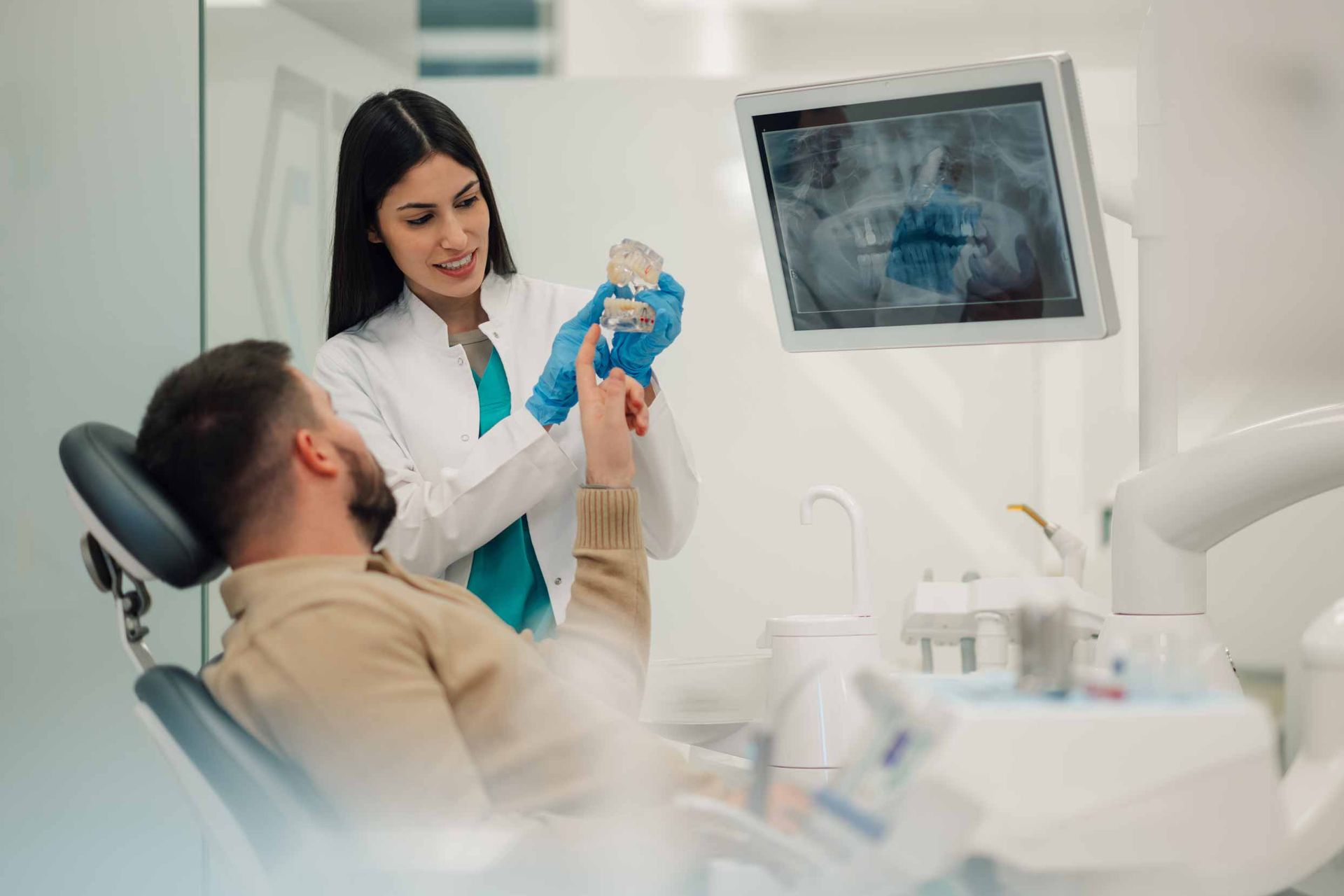 Dentist showing a patient a dental model during a restorative consultation. Dentist showing a patient a dental model during a restorative consultation.