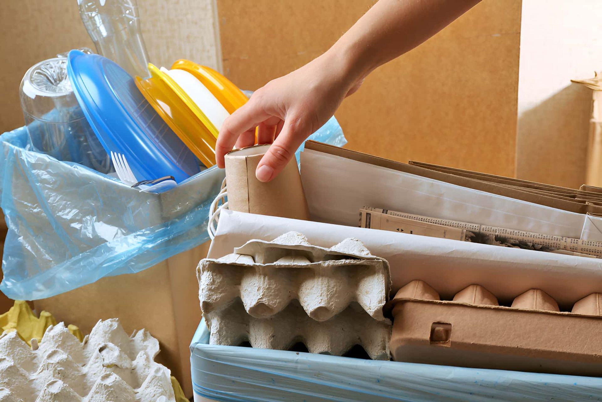 A Person Is Picking Up A Yellow Lid From A Box — North Queensland Recycling Agents In Bungalow, QLD