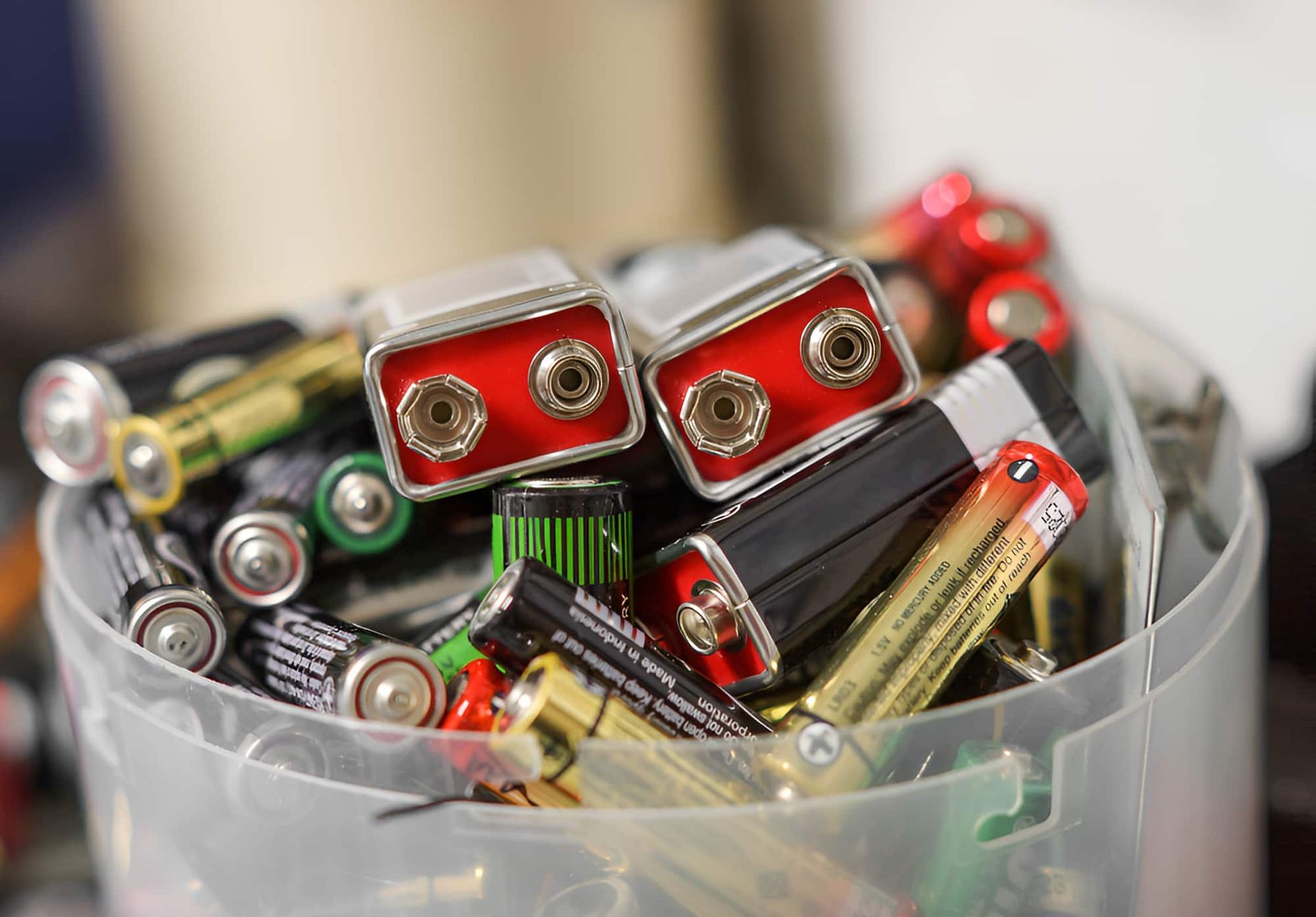 A Pile Of Batteries In A Plastic Container On A Table — North Queensland Recycling Agents In Bungalow, QLD