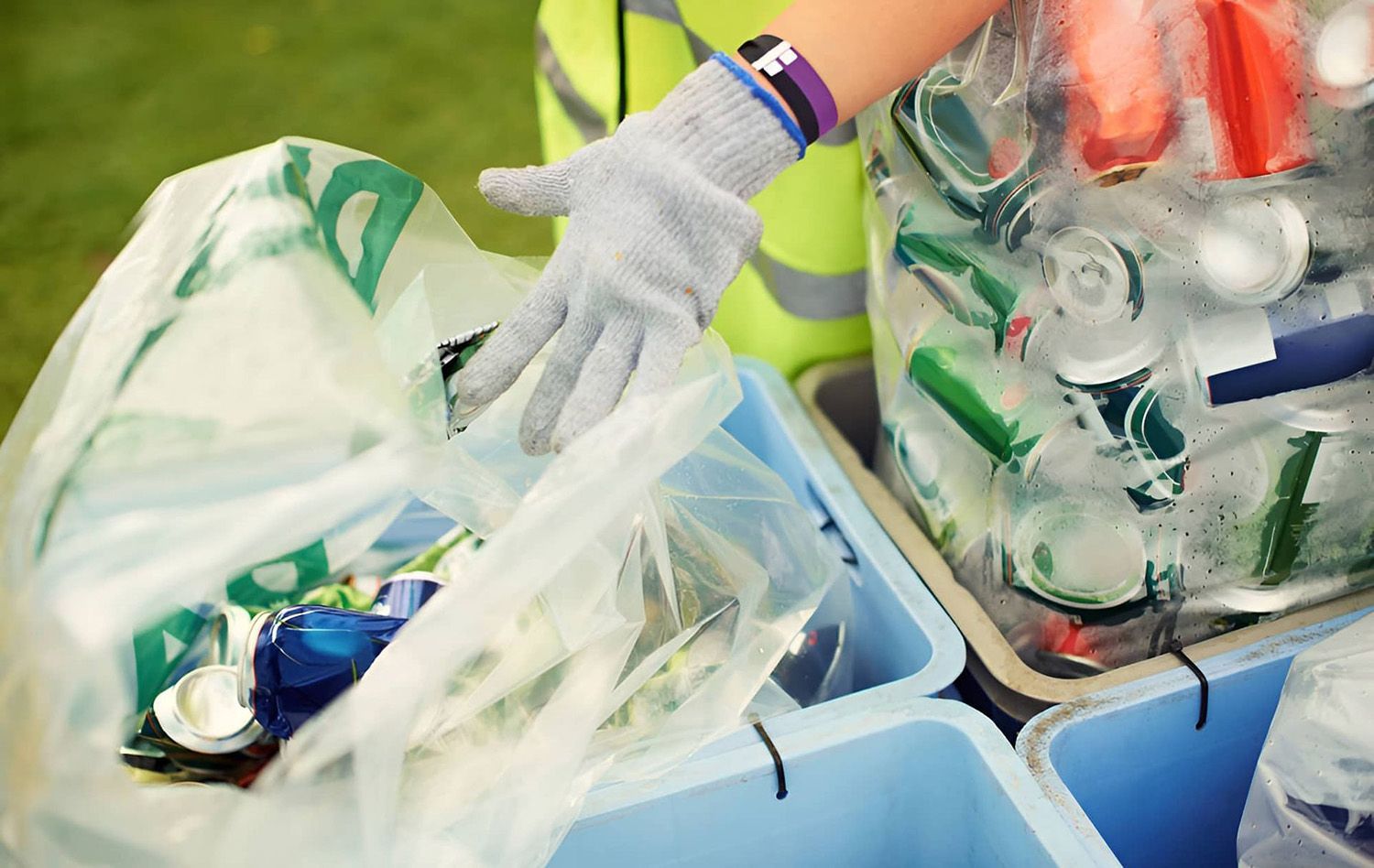 Person Wearing a Glove Sorting Recyclables Into Blue Bins
