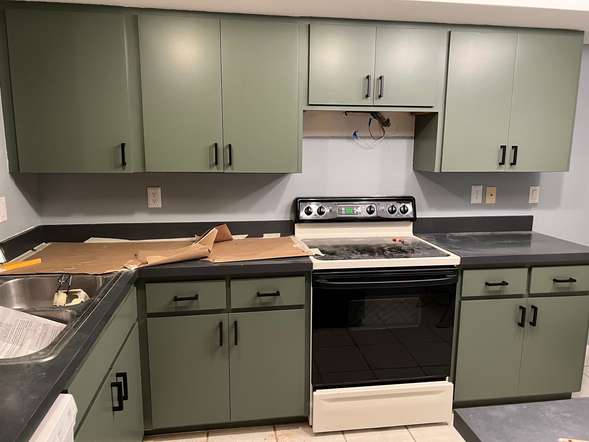 a kitchen with green cabinets and a black stove