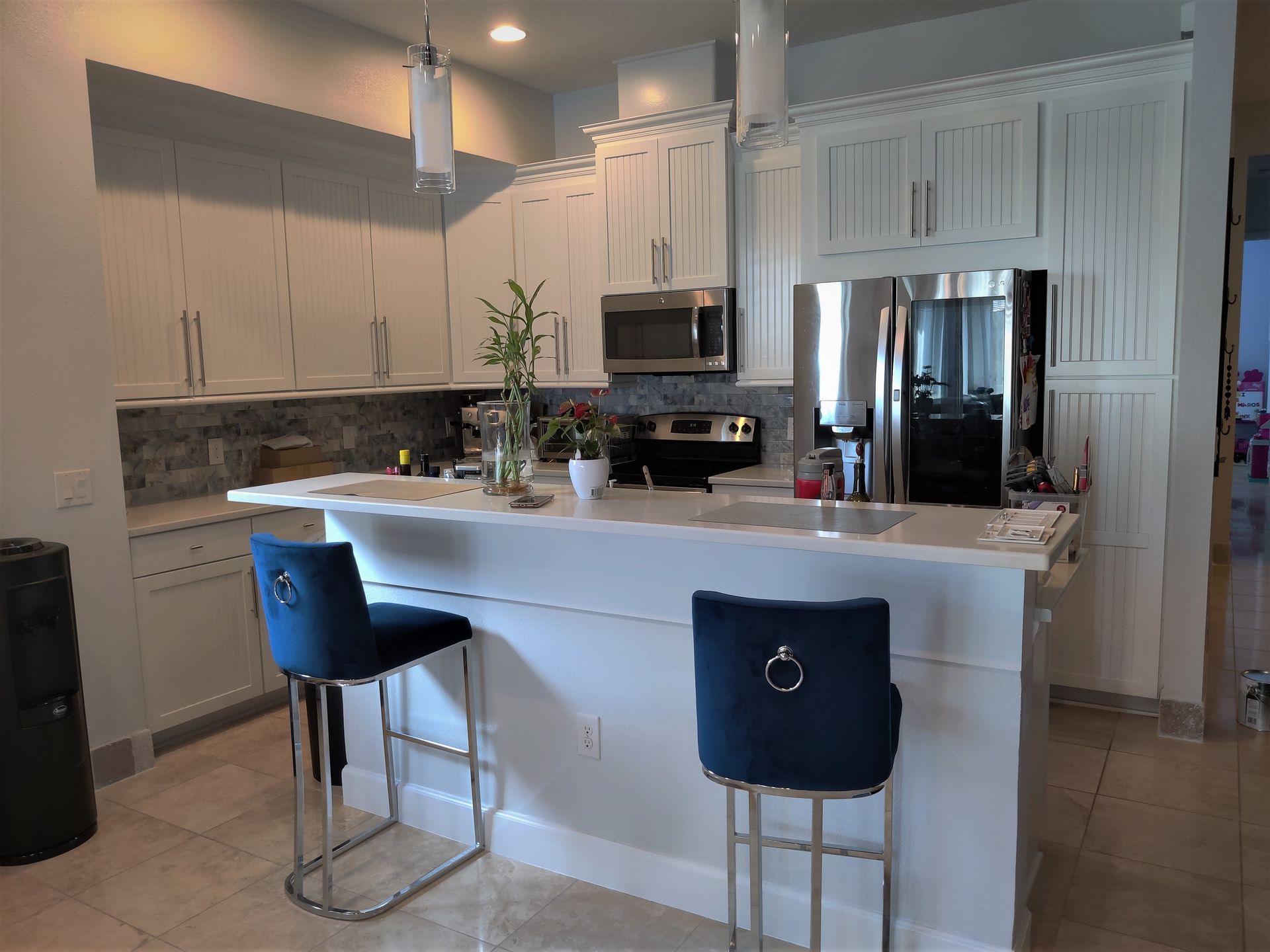 a kitchen with white cabinets and blue bar stools