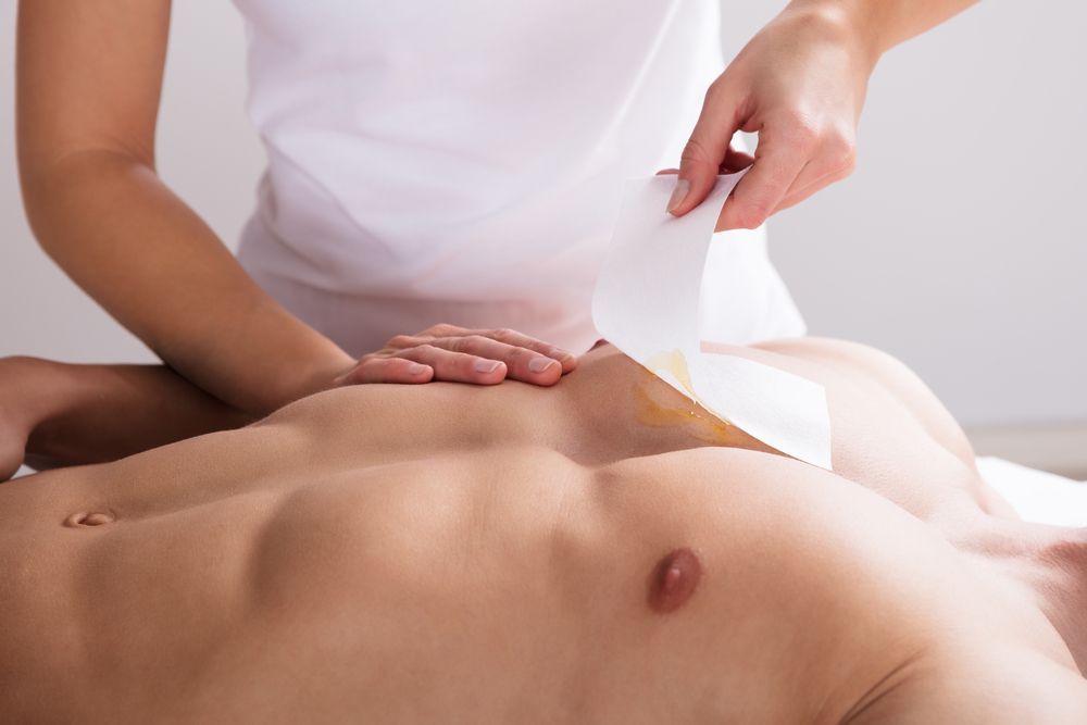 A woman is waxing a man 's chest in a beauty salon.