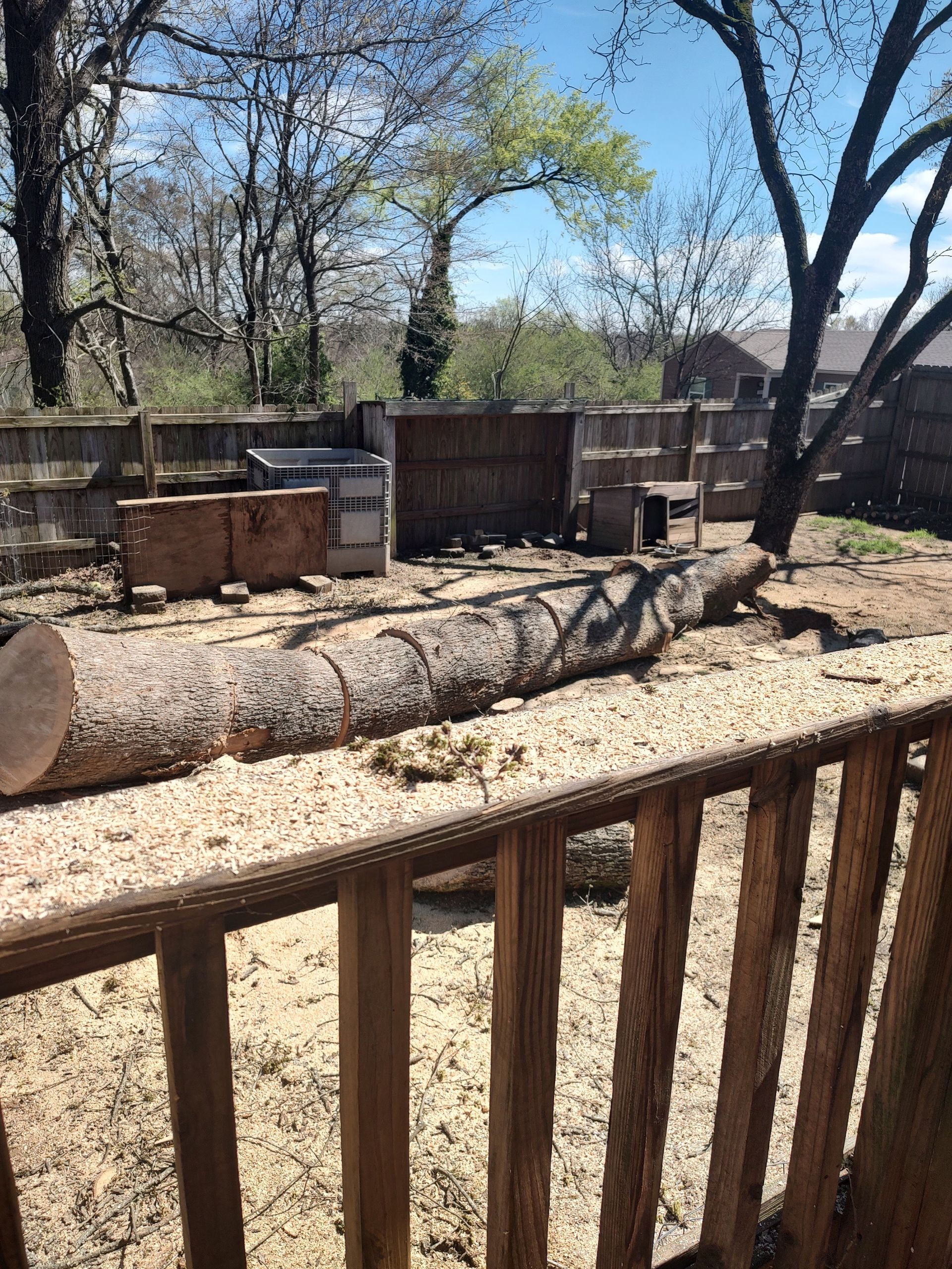 A large log is sitting on top of a wooden fence.