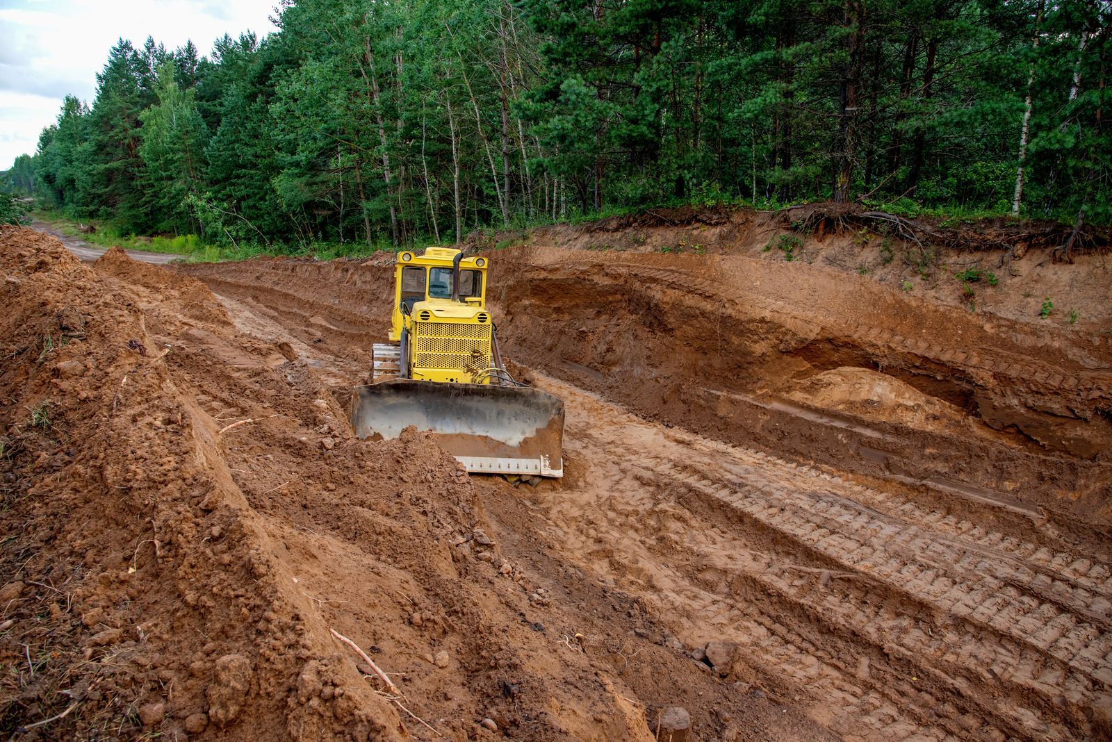 A bulldozer is moving dirt on a muddy road.