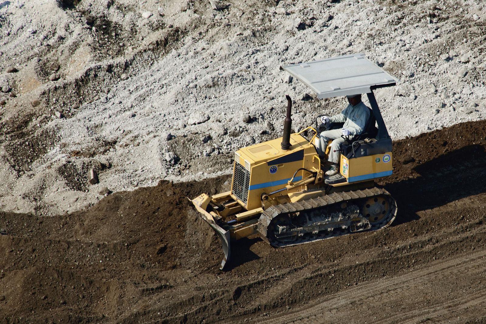 A man is driving a bulldozer on a dirt road.