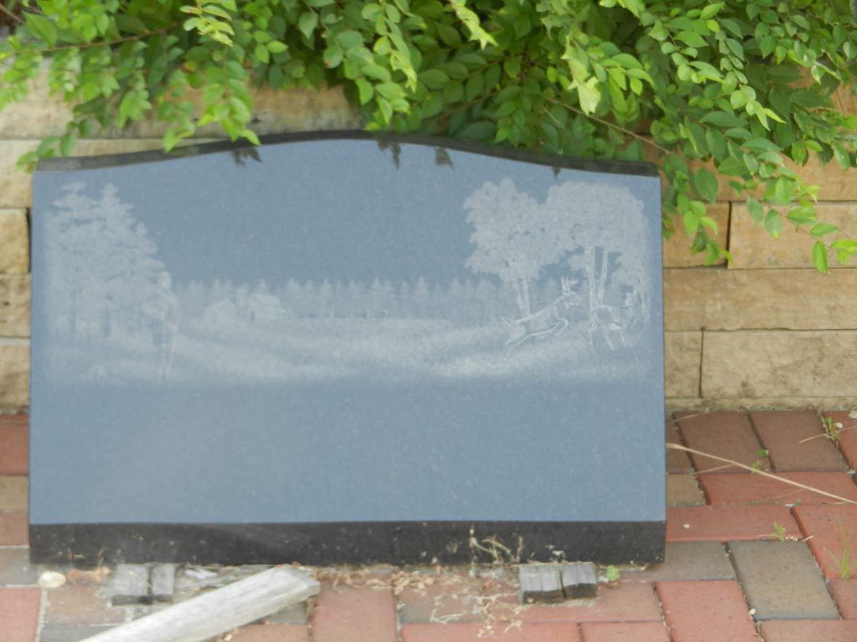 A gravestone with a picture of trees on it