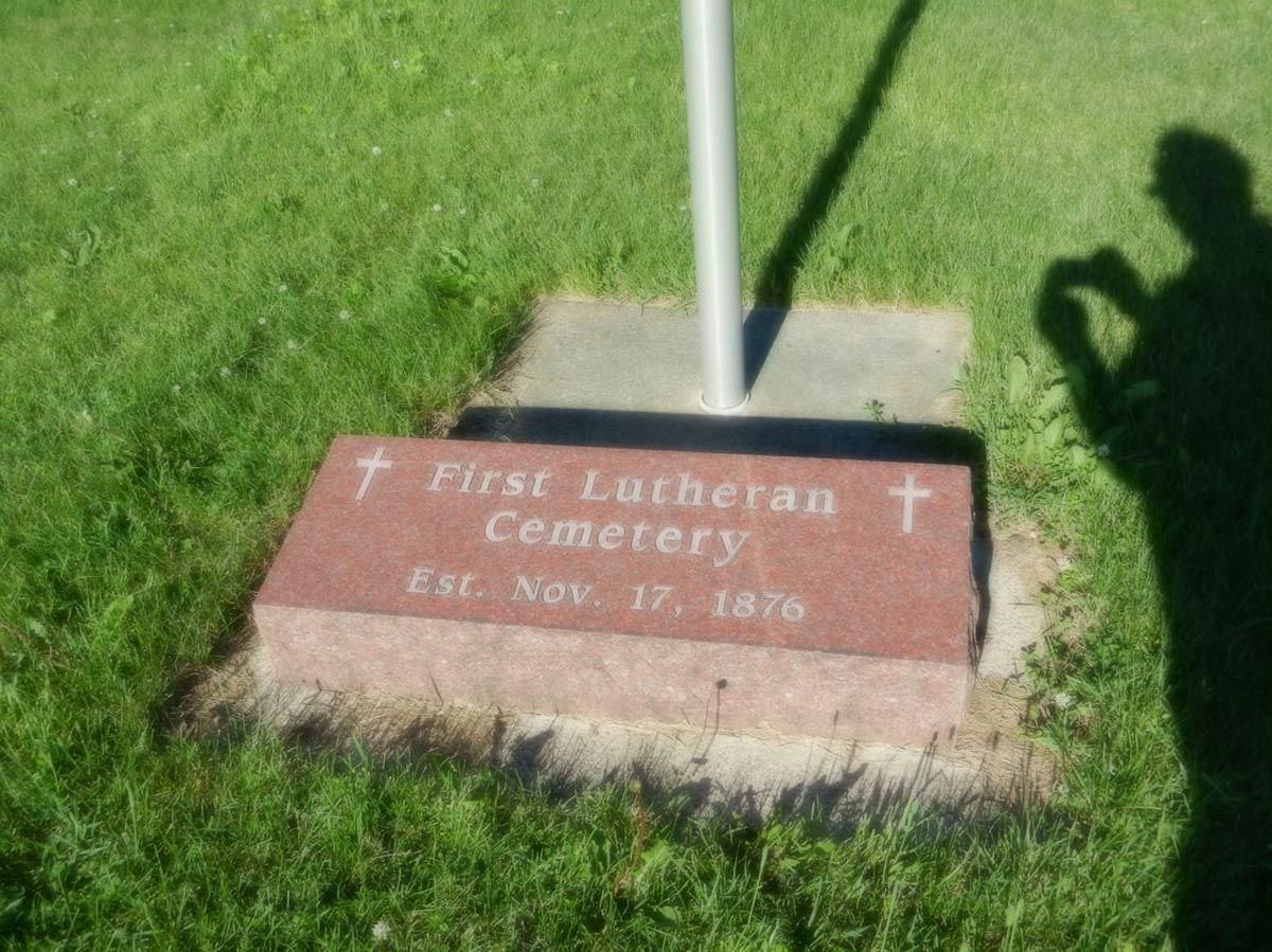 A gravestone in the grass that says first lutheran cemetery