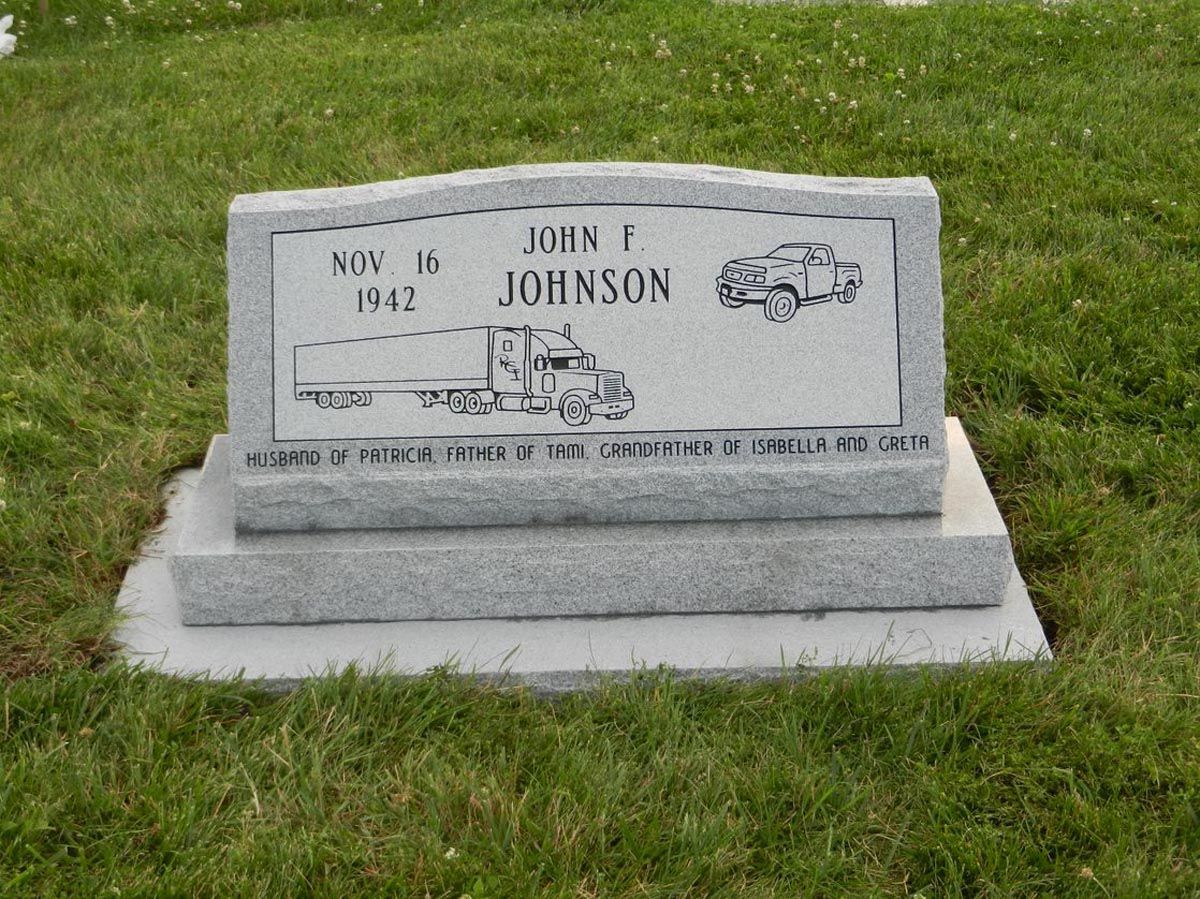 A gravestone in a cemetery with a truck on it