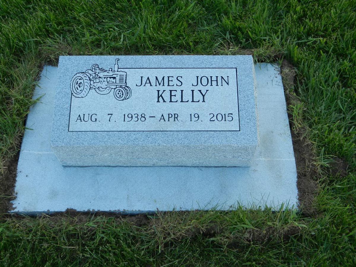A gravestone for james john kelly is in the grass.