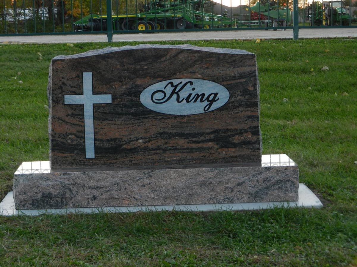 A gravestone for king with a cross on it in a cemetery