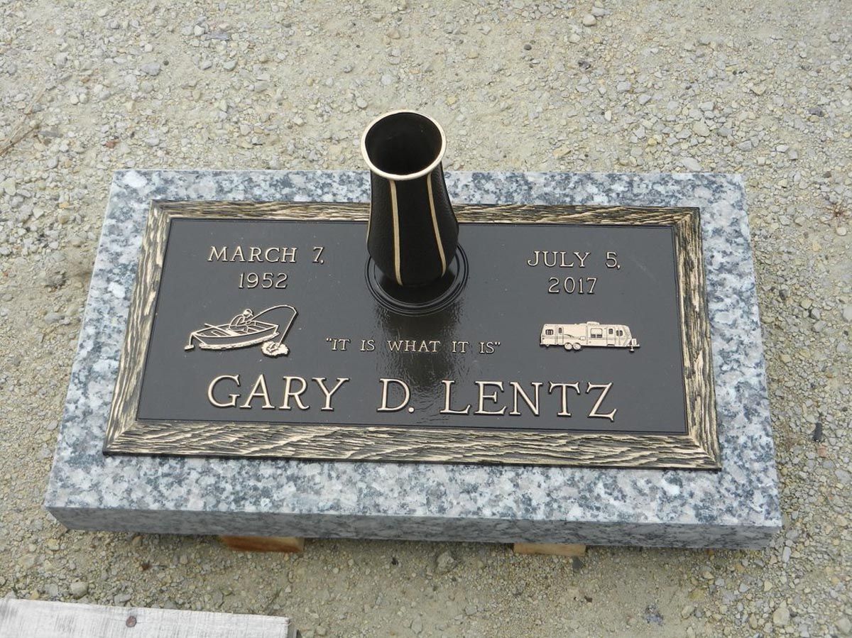 A grave marker for gary d lentz with a vase on top