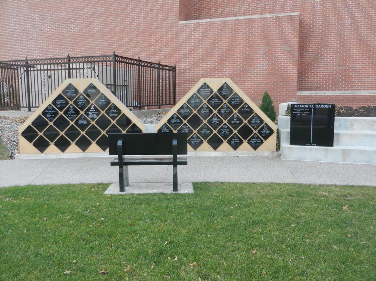A black bench sits in front of a brick wall