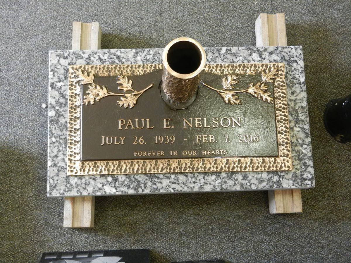 A gravestone for paul e nelson with a vase in the middle