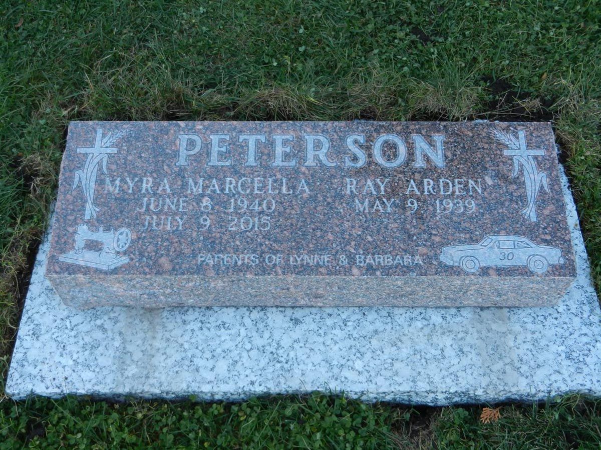 A gravestone for peterson is sitting on top of a lush green field