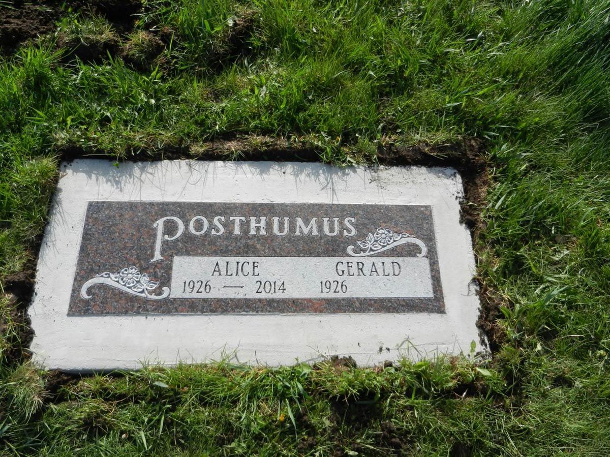 A gravestone in the grass with the name posthumus on it