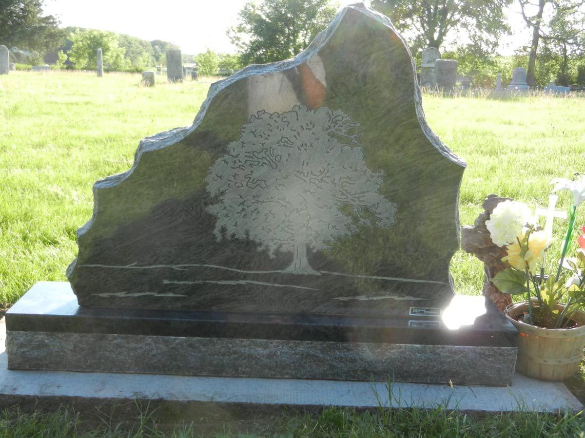 A gravestone with a tree on it in a cemetery