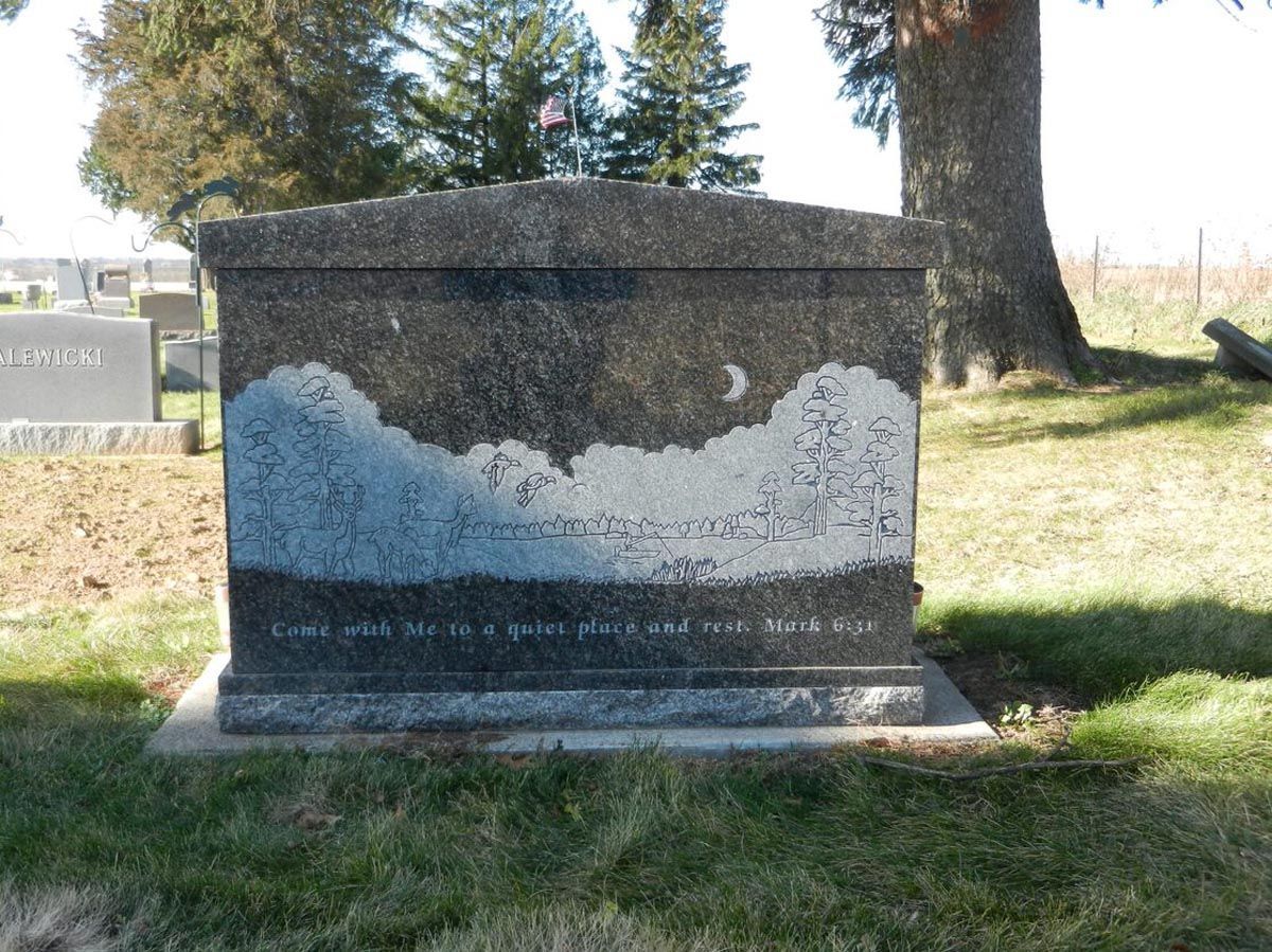 A gravestone in a cemetery with a tree in the background