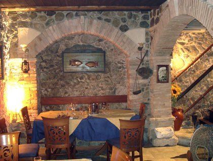Un tavolo apparecchiato con una tovaglia gialla e blu in un ristorante con muri in pietra