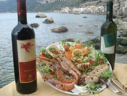 Un piatto a base di pesce alla griglia, scampi e due bottiglie di vino