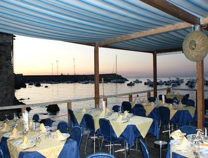 tavoli apparecchiati sotto una copertura all'esterno del ristorante vista mare