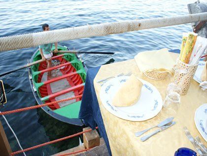 Un tavolo apparecchiato e sotto un ragazzo in barca che rema