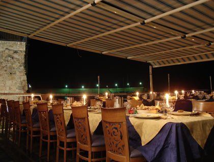 Dei tavoli apparecchiati con delle candele sotto una copertura all'esterno del ristorante