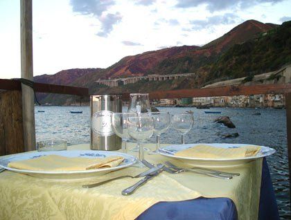 Un tavolo apparecchiato con dei bicchieri e vista del mare e delle montagne