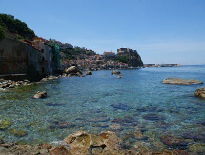 Mare con acqua cristallina, scogli e vista di un paesino