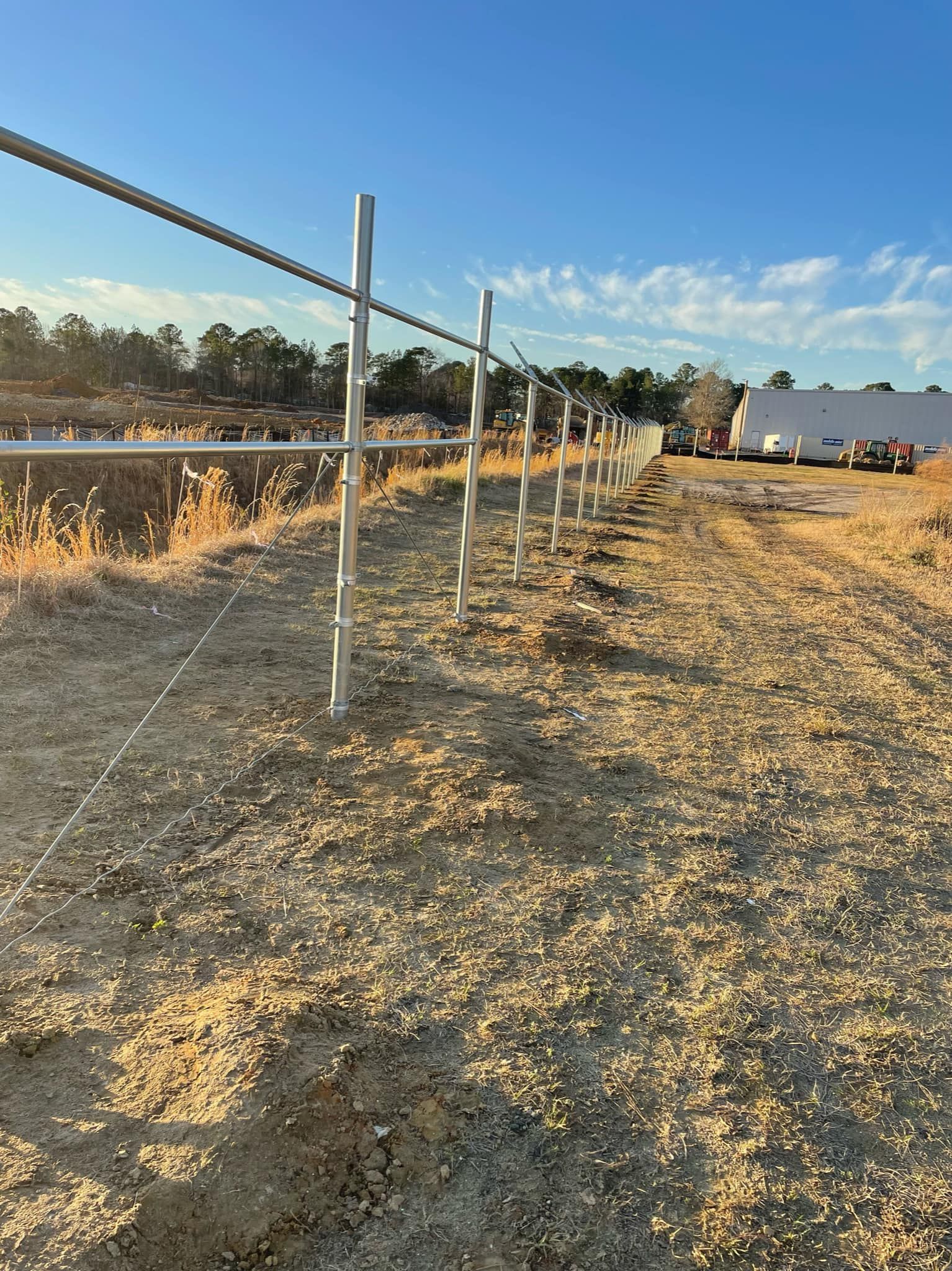 A fence is being built in the middle of a dirt road.