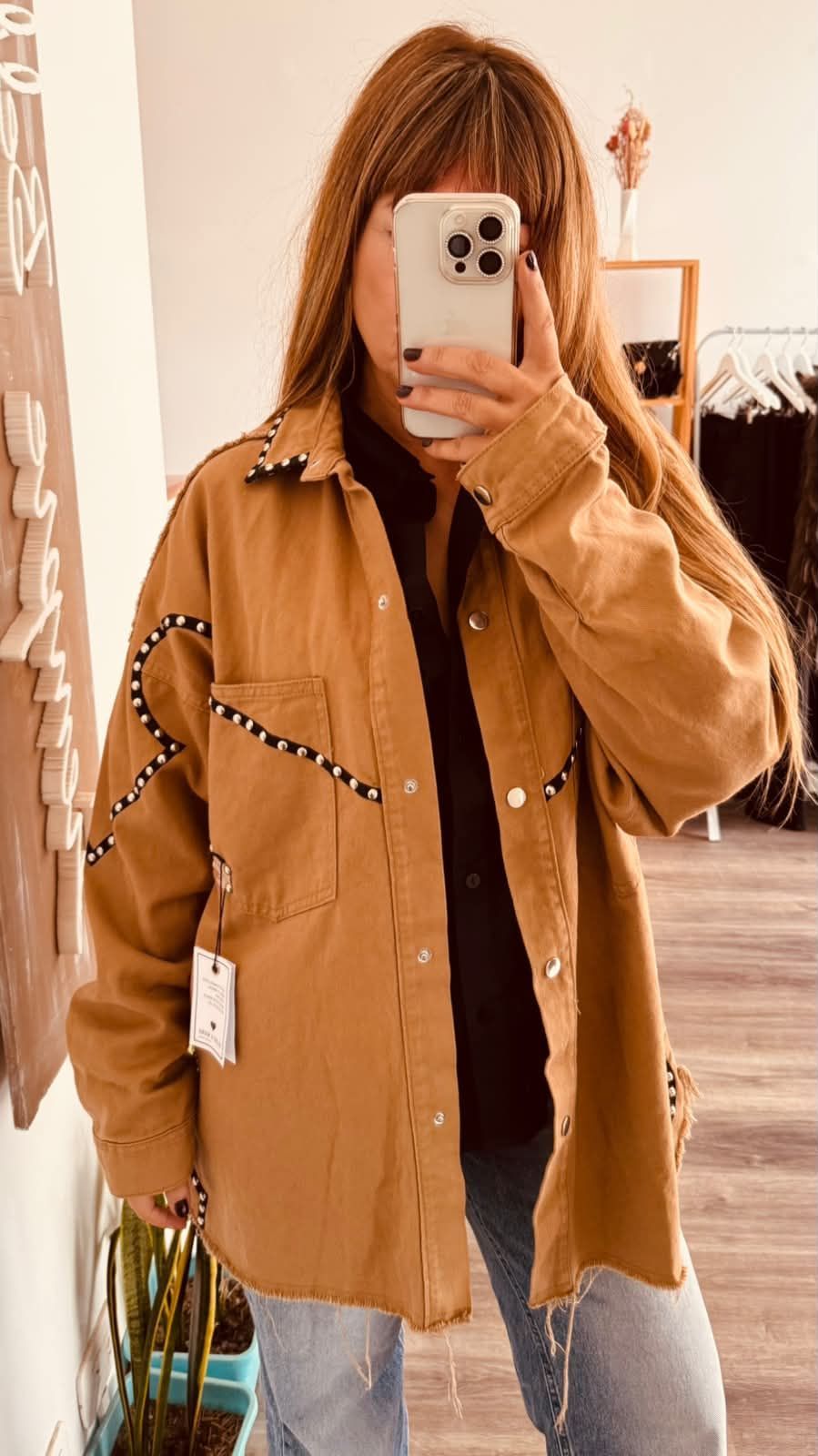 Selfie frente al espejo, con una chaqueta color canela y vaqueros.