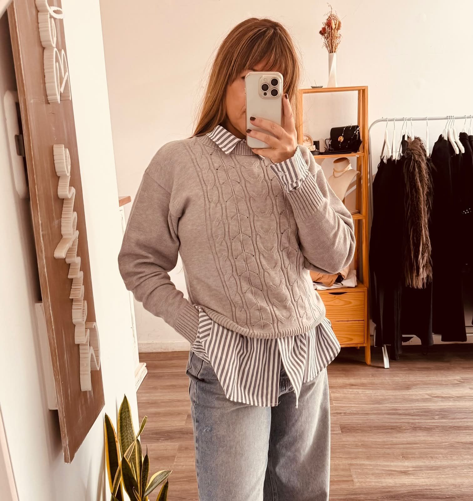 Una persona se toma una selfie frente al espejo en una tienda de ropa.