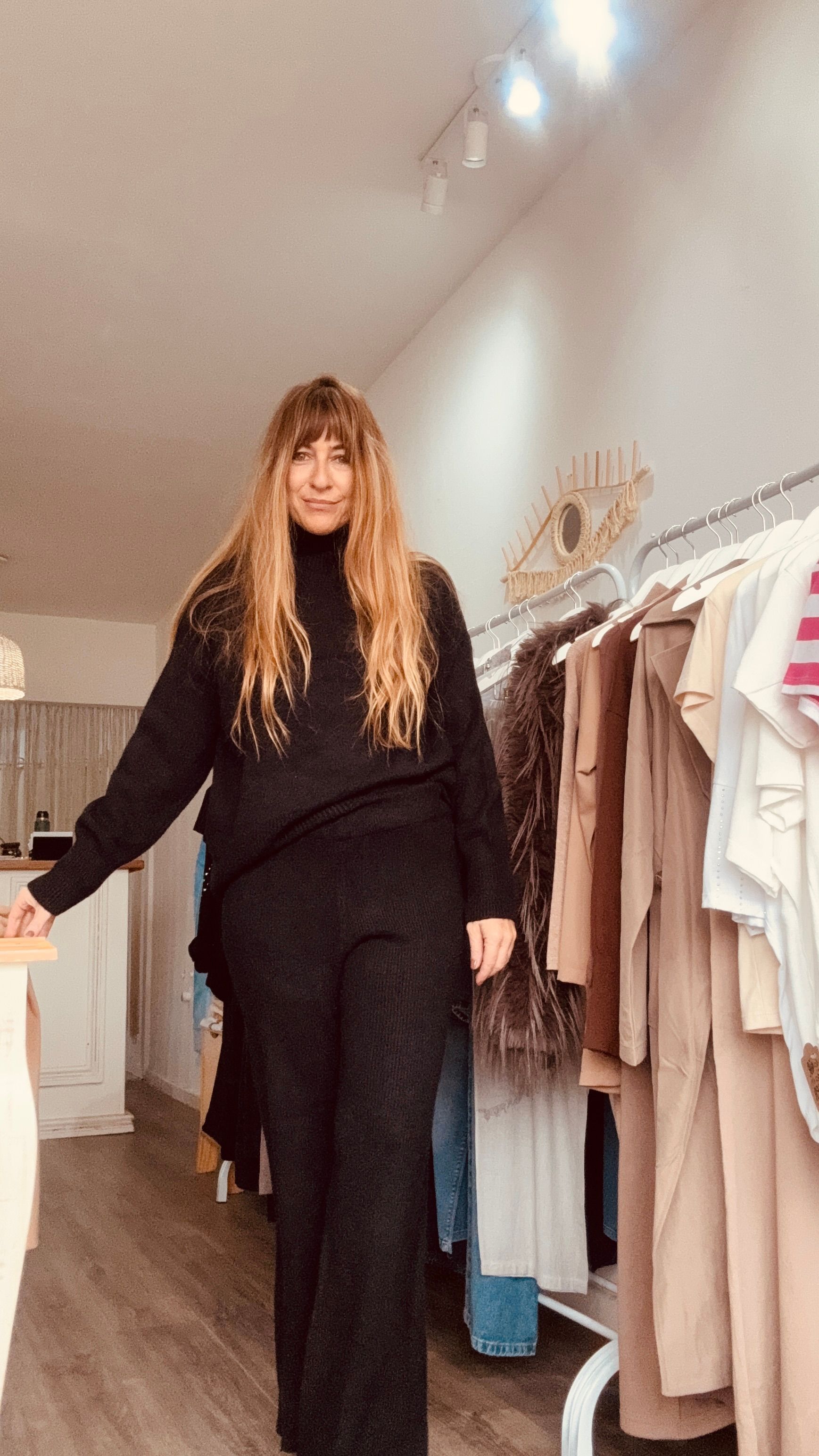 Una persona se toma una selfie frente al espejo en un probador de una tienda de ropa.