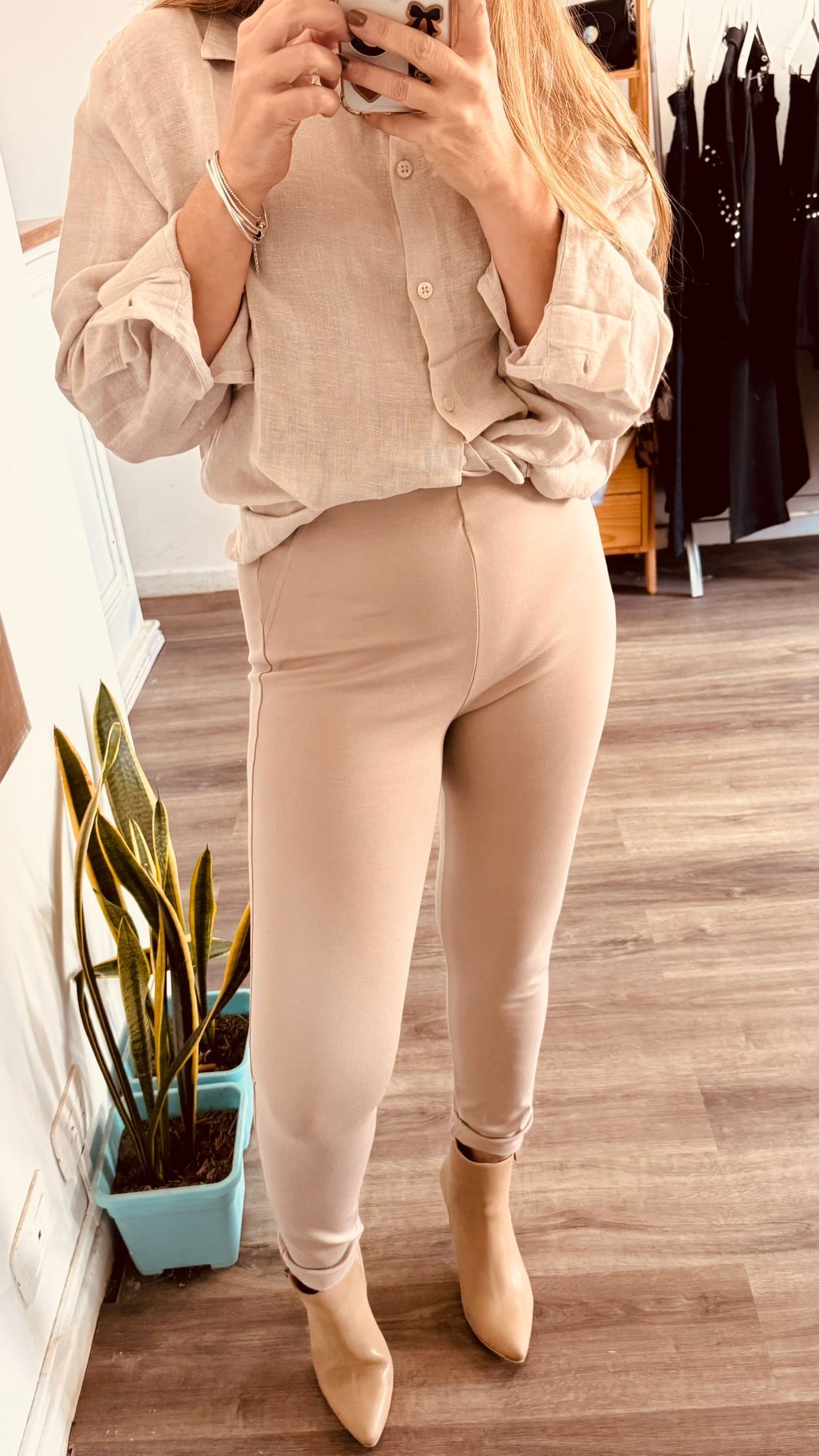 Persona con pantalones beige y botas color canela de pie en el interior de un edificio sobre un suelo de madera.