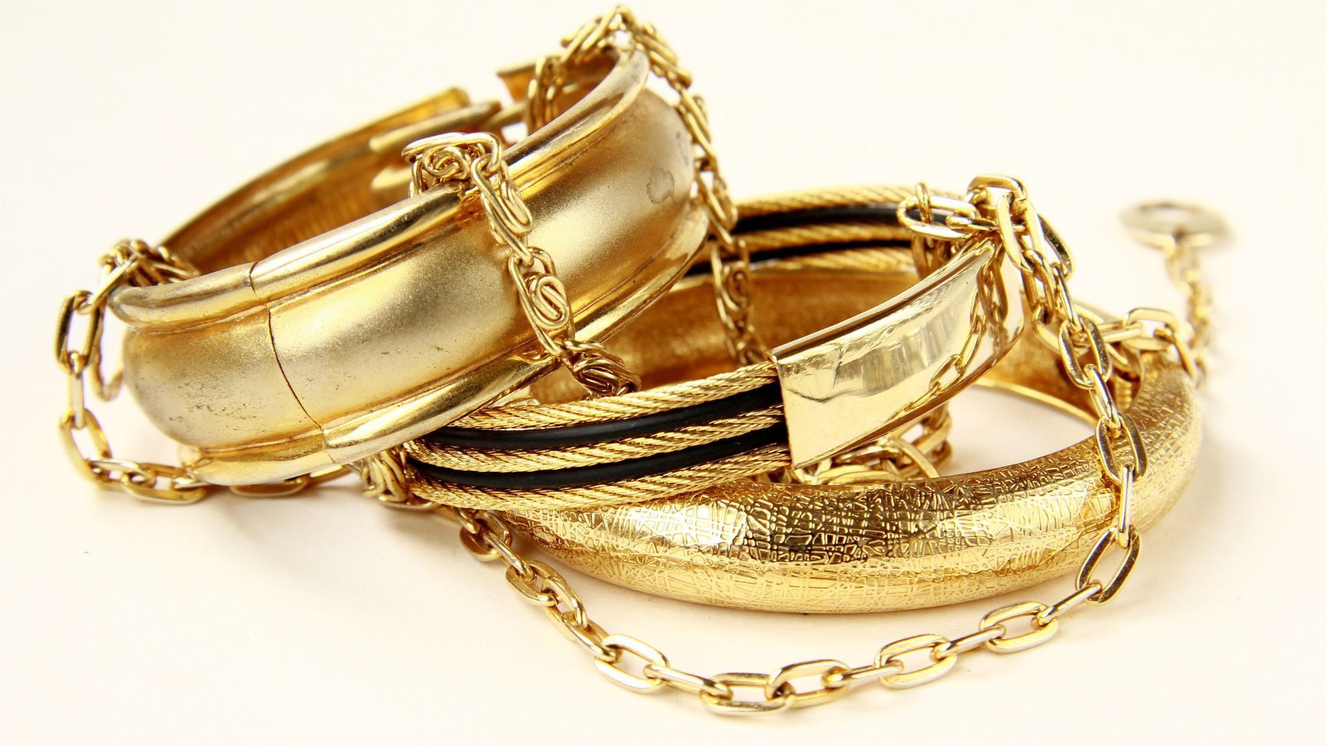 A pile of gold bracelets and chains on a white background