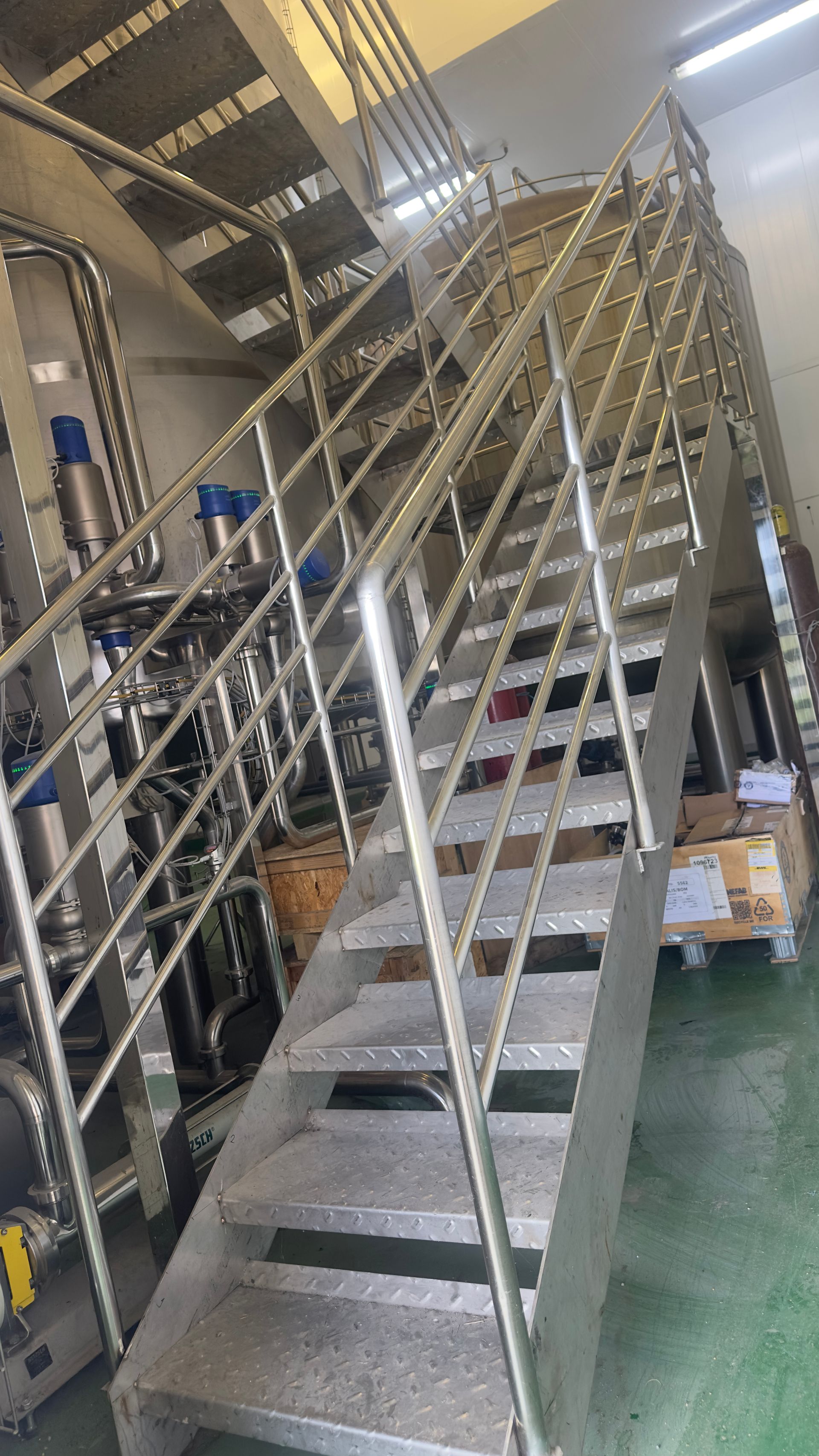 Escada com corrimão de metal que leva ao andar superior, ambiente industrial com maquinário.