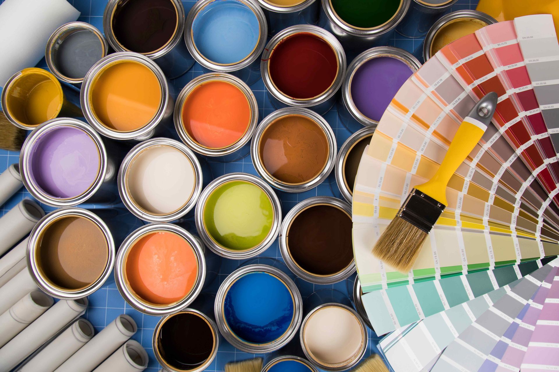 A bunch of cans of paint and a brush on a table