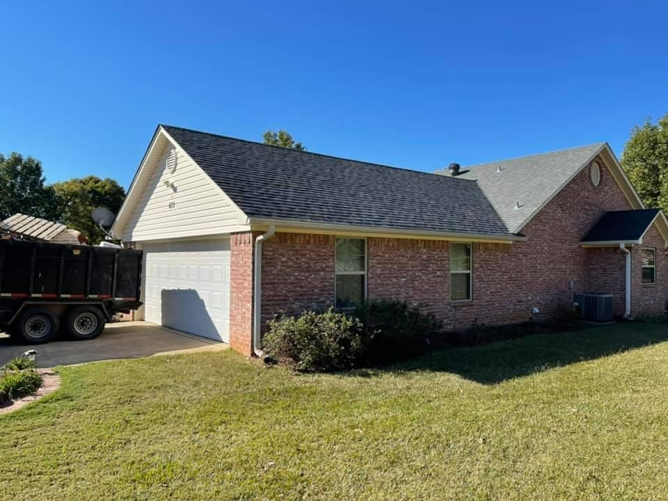 Brick house with a new dark roof and attached garage, under a blue sky.
