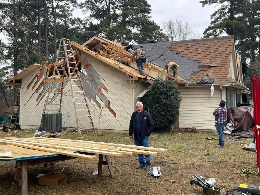 House roof partially demolished, workers on roof, man in yard, tools, wood.